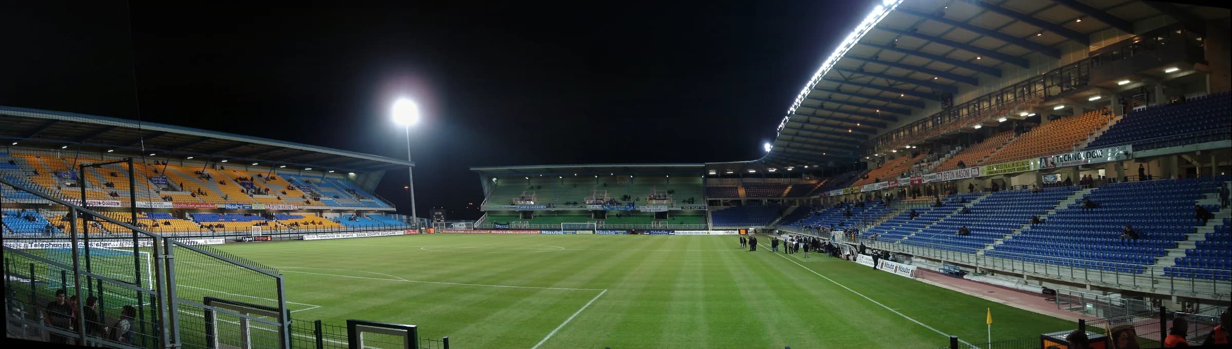 Panorama nocturne du stade de l’Aube, avec pelouse et tribunes.